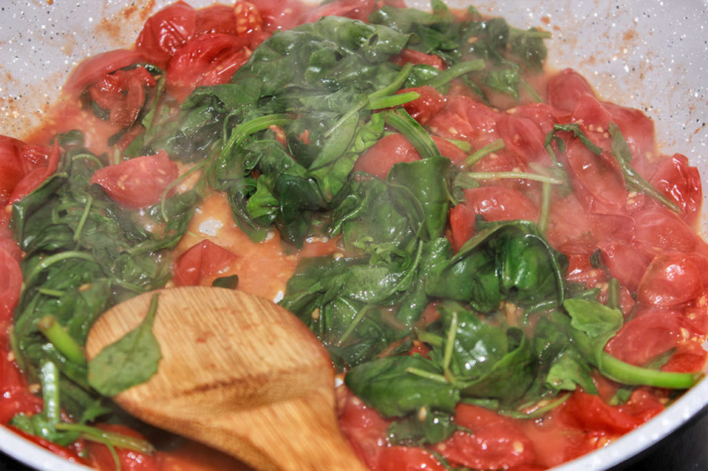 Spinat, Rucola und Tomate in Pfanne zubereitet