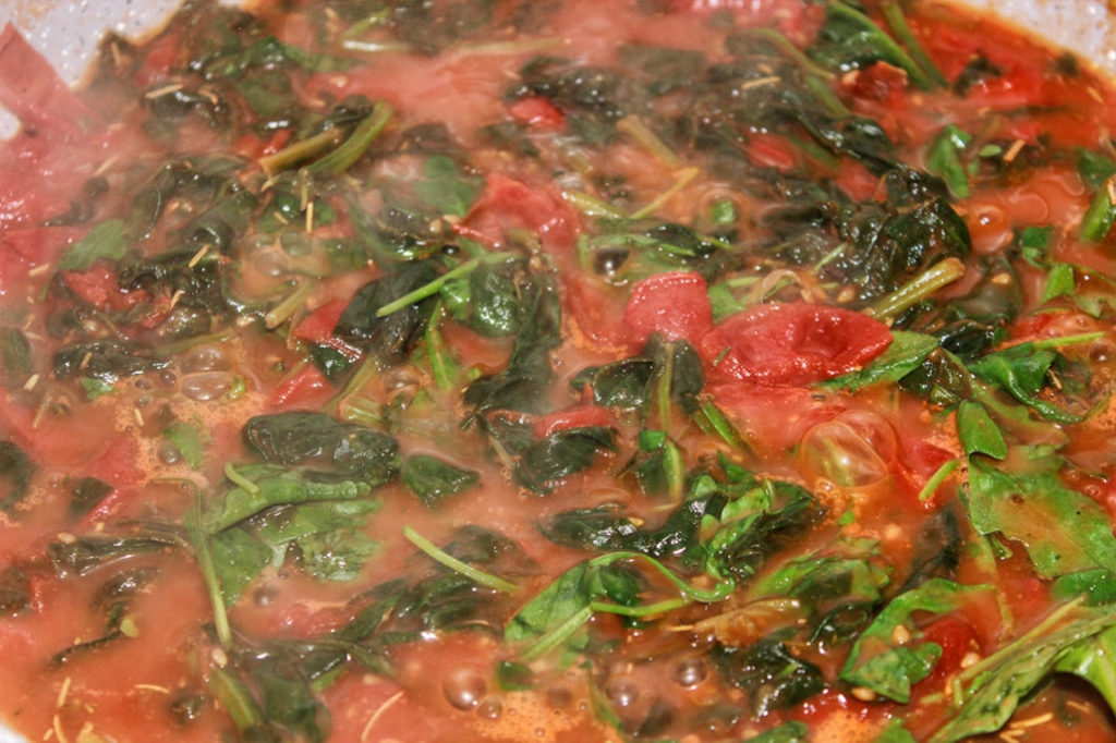 Spinat, Rucola und Tomaten in Pfanne